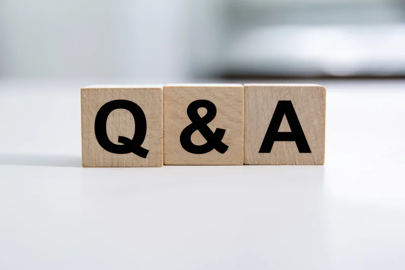 Wooden blocks with bold black letters spelling q and a arranged neatly on a white surface