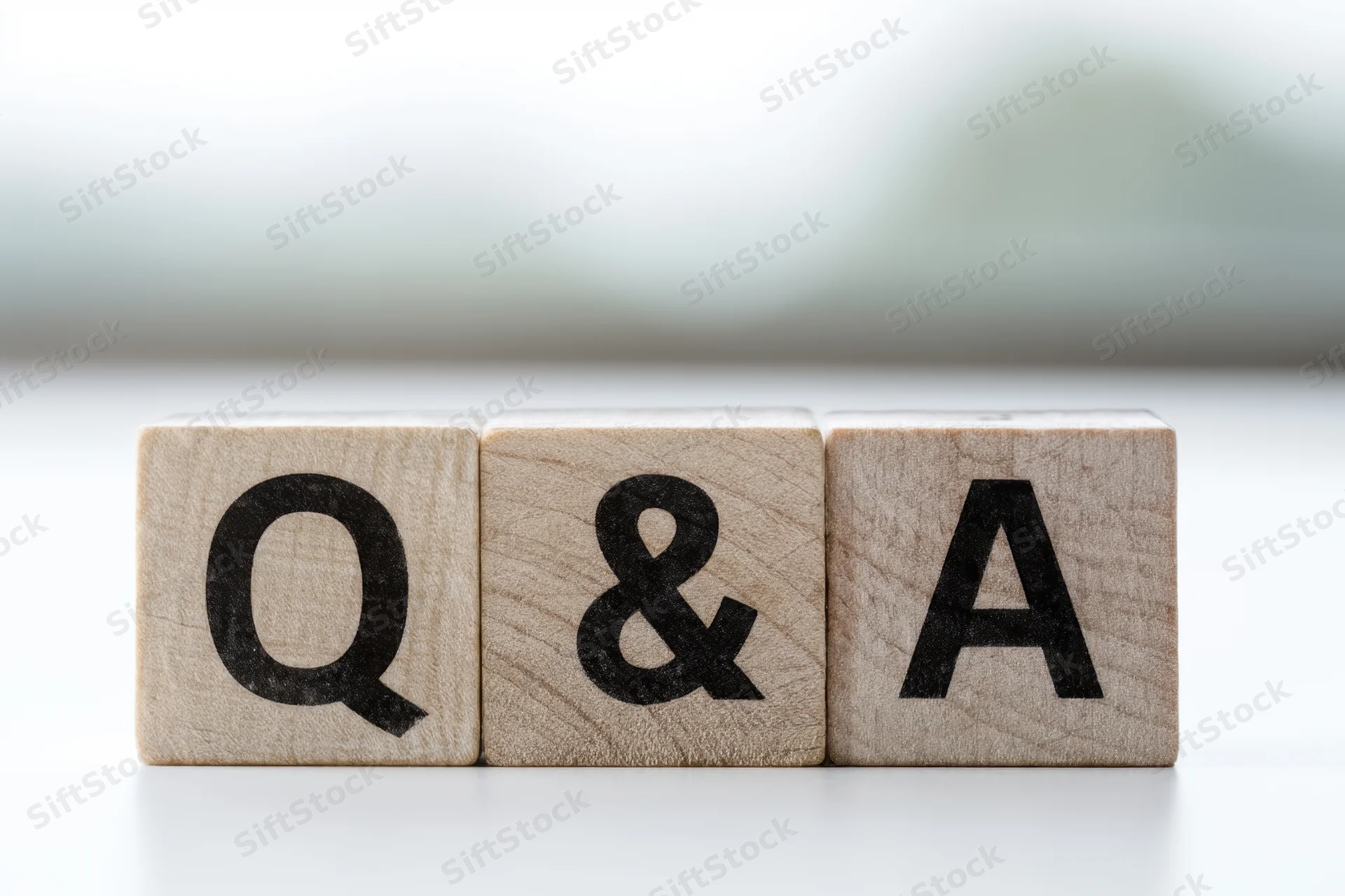 Wooden blocks with bold black letters spelling q and a arranged in a row on a white surface