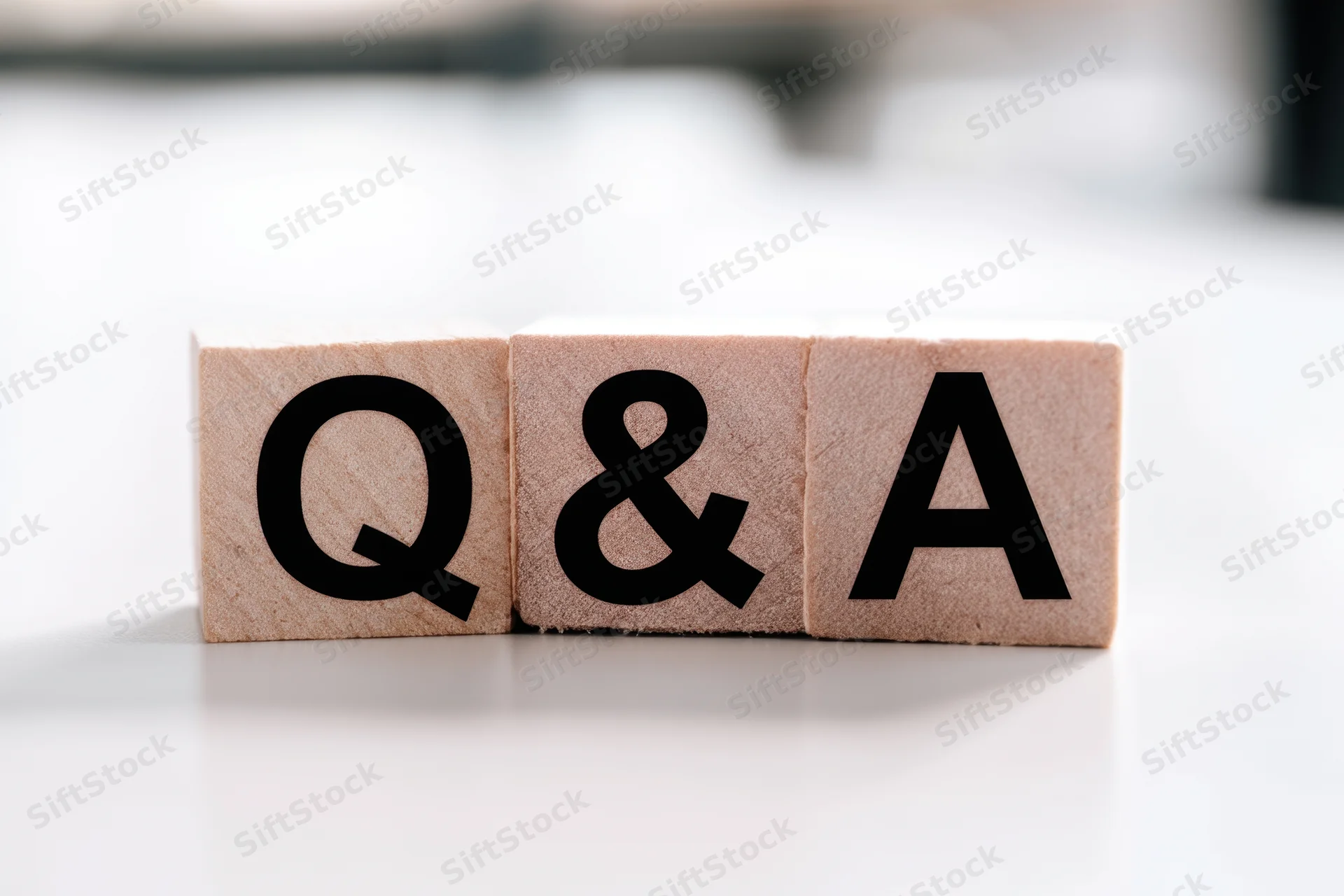 Wooden blocks with bold black letters spelling q&a arranged neatly on a white surface