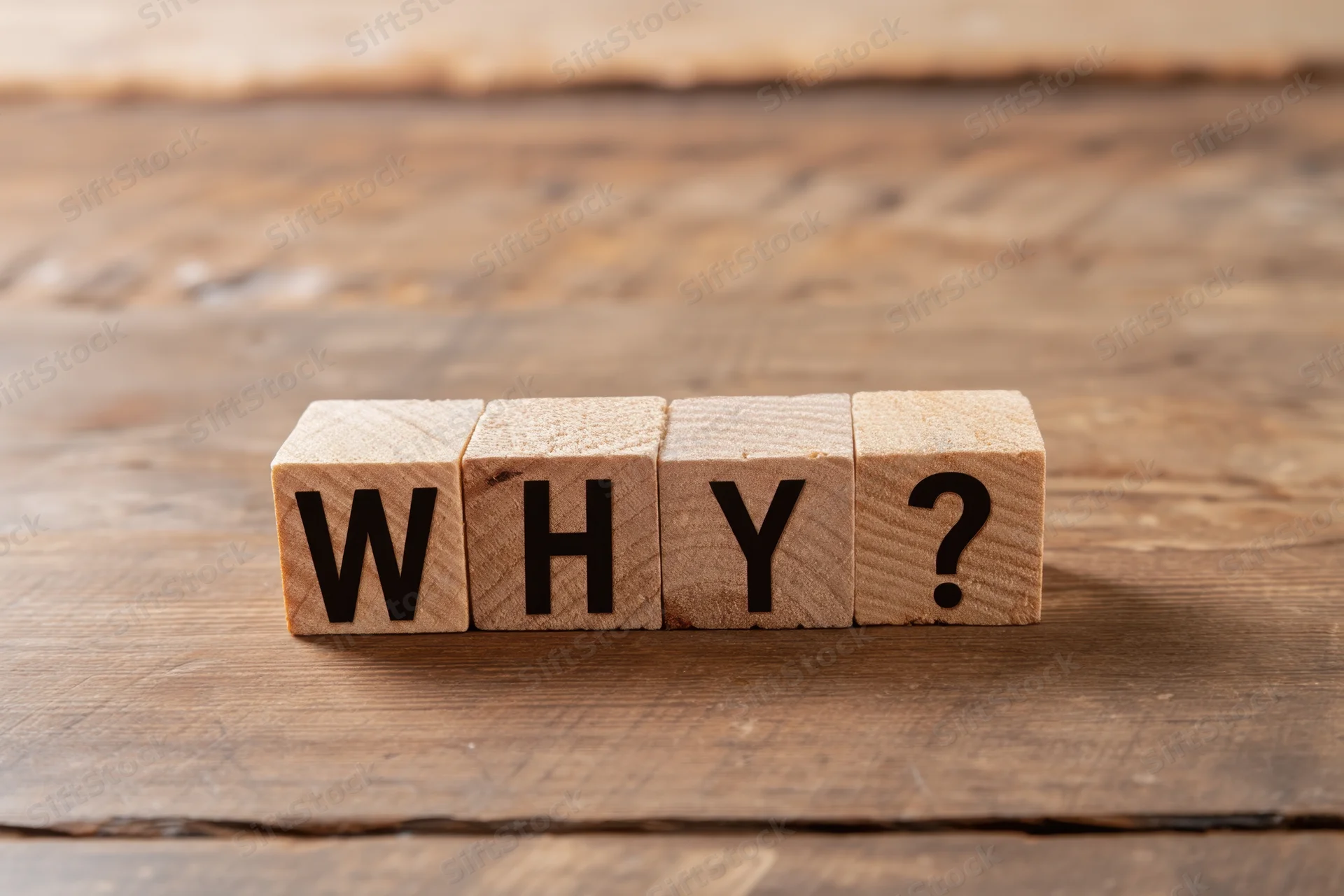 Wooden blocks arranged to spell why with a question mark on a rustic wooden surface
