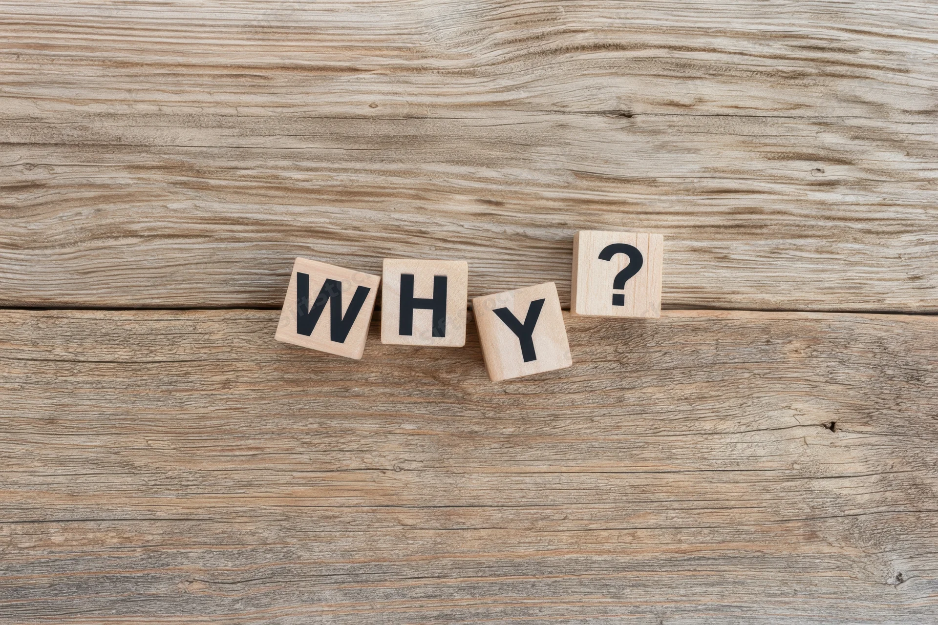 Wooden blocks spelling why with a question mark on a rustic wood surface