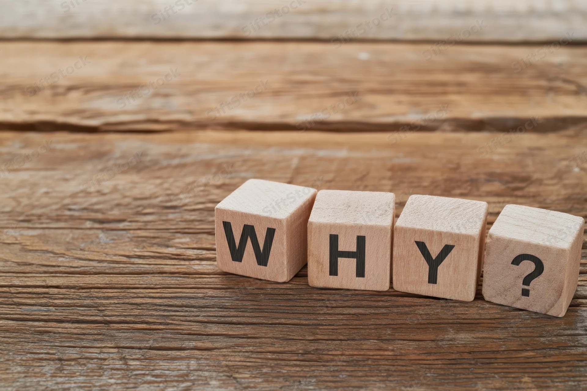 Wooden blocks spelling why with a question mark on a rustic wooden surface