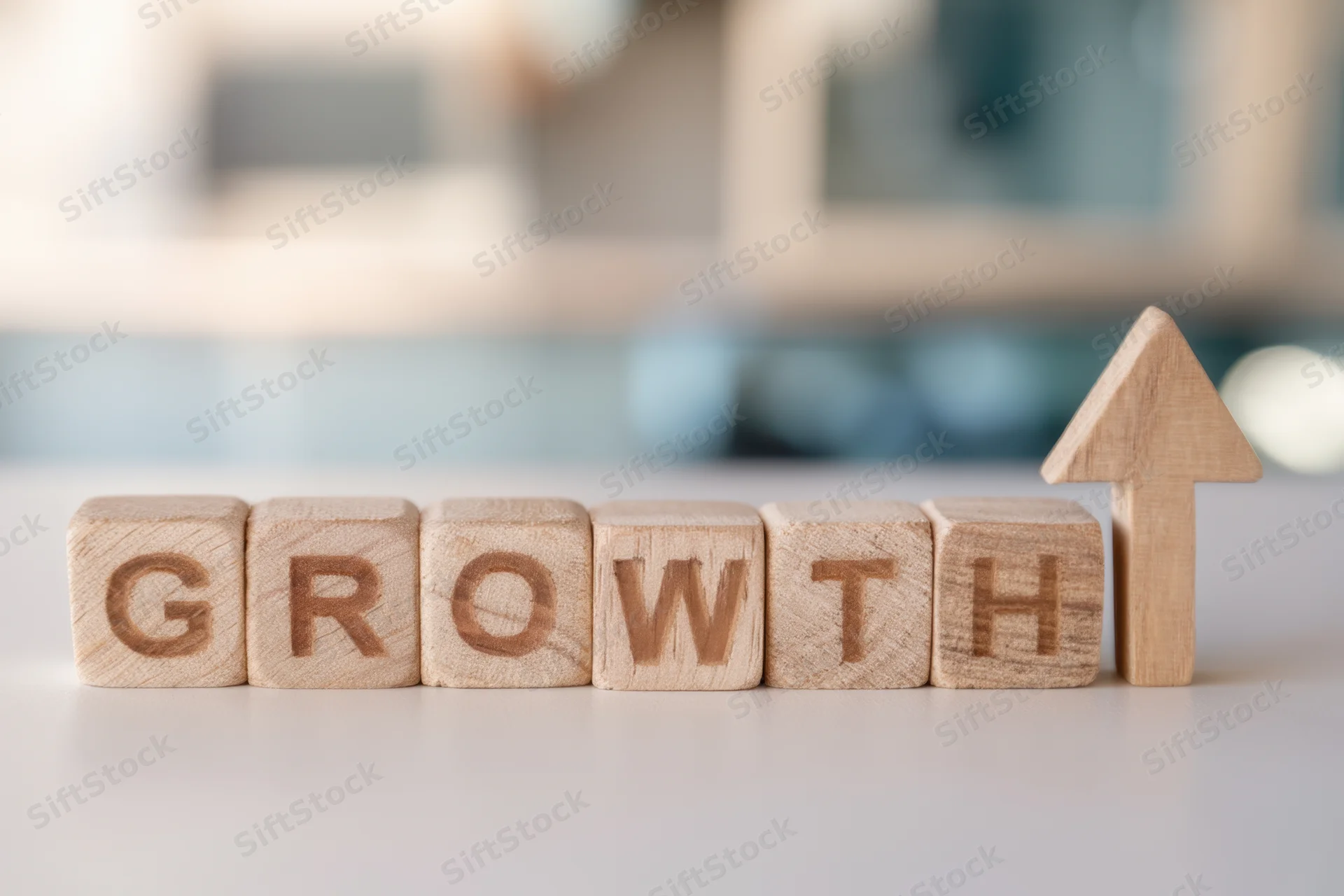 Wooden blocks spelling growth with an upward arrow on a desk surface