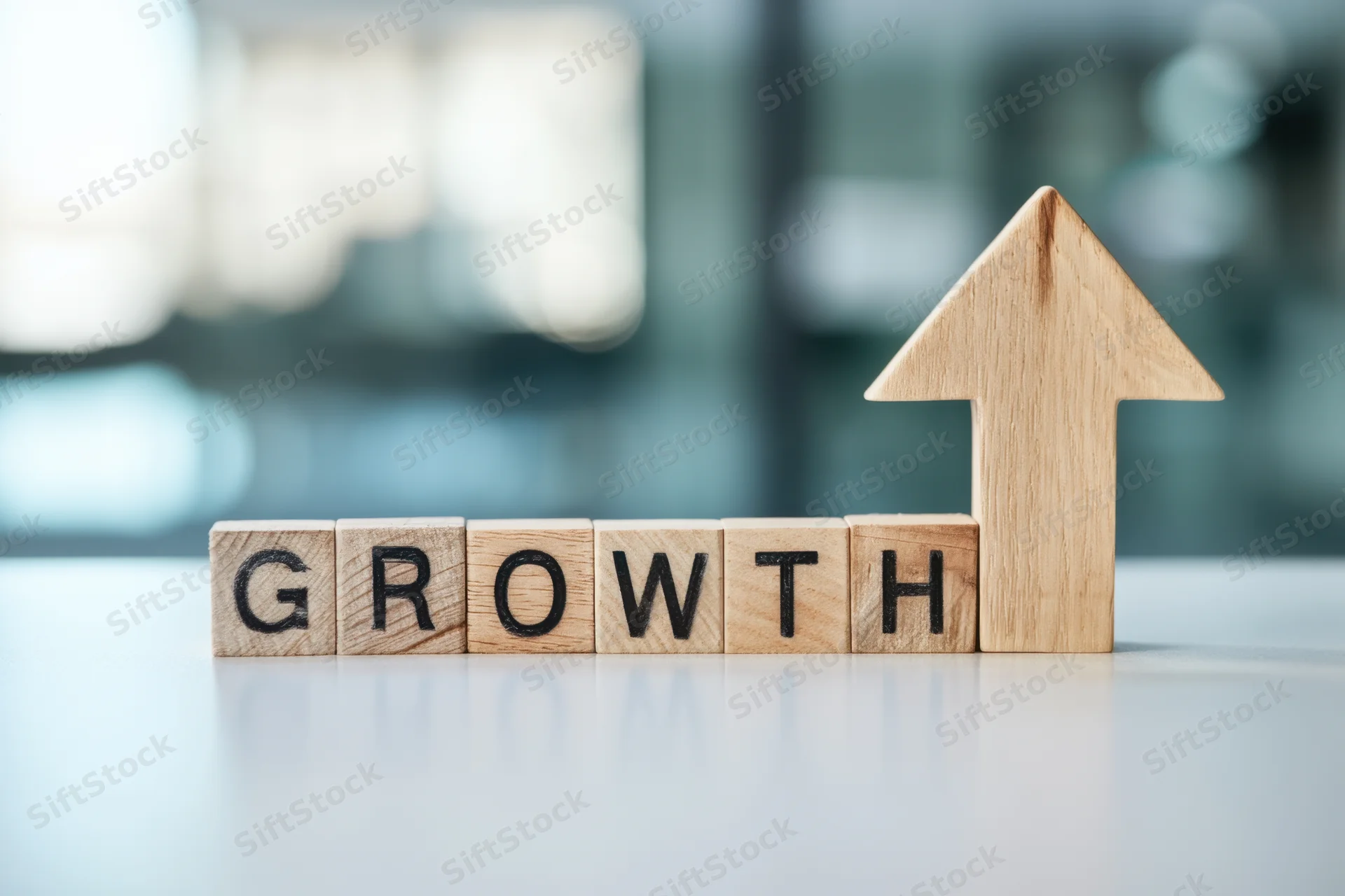 Wooden blocks spelling growth with an arrow pointing up on a desk