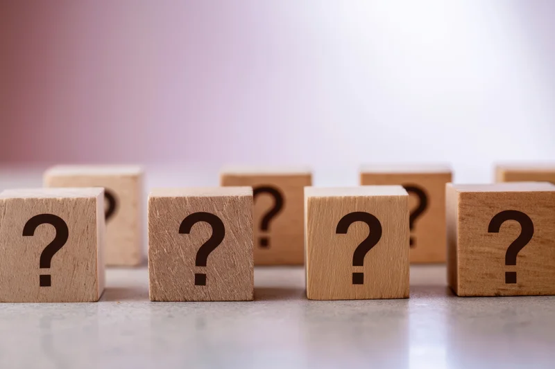 Wooden cubes with question marks arranged in a row on a smooth surface