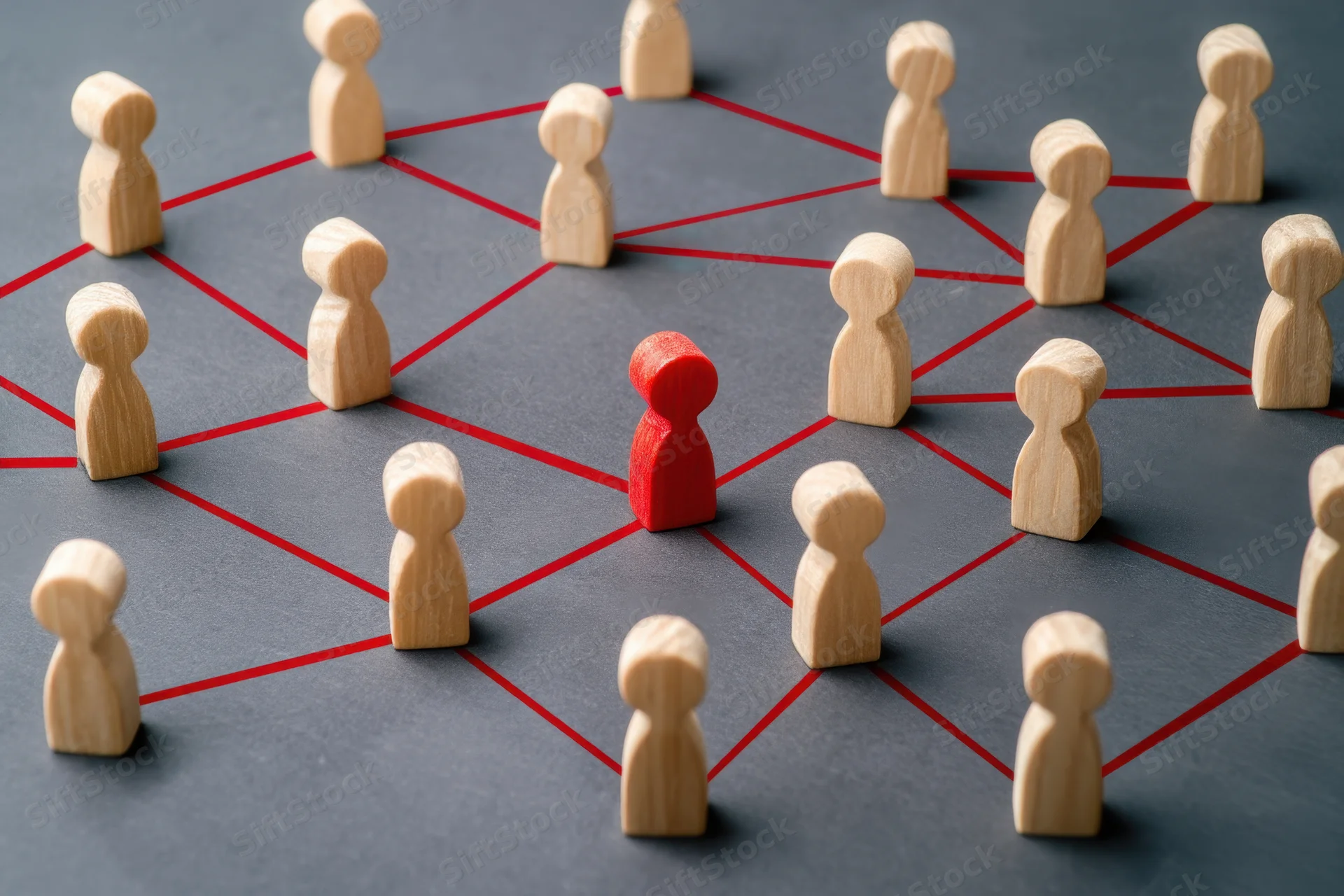 Wooden tokens arranged in a network grid with one red token at center on gray surface