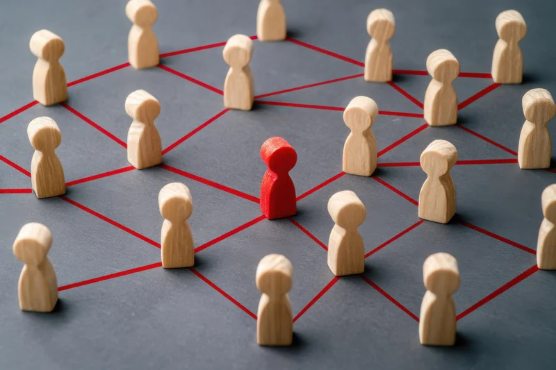 Wooden tokens arranged in a network grid with one red token at center on gray surface