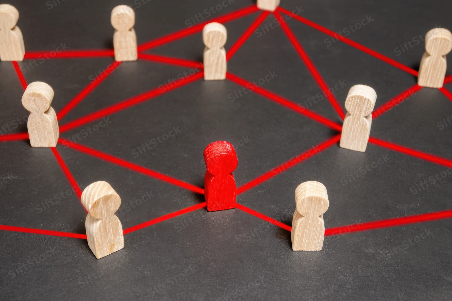 Wooden tokens connected by red strings arranged in a network pattern on a dark surface