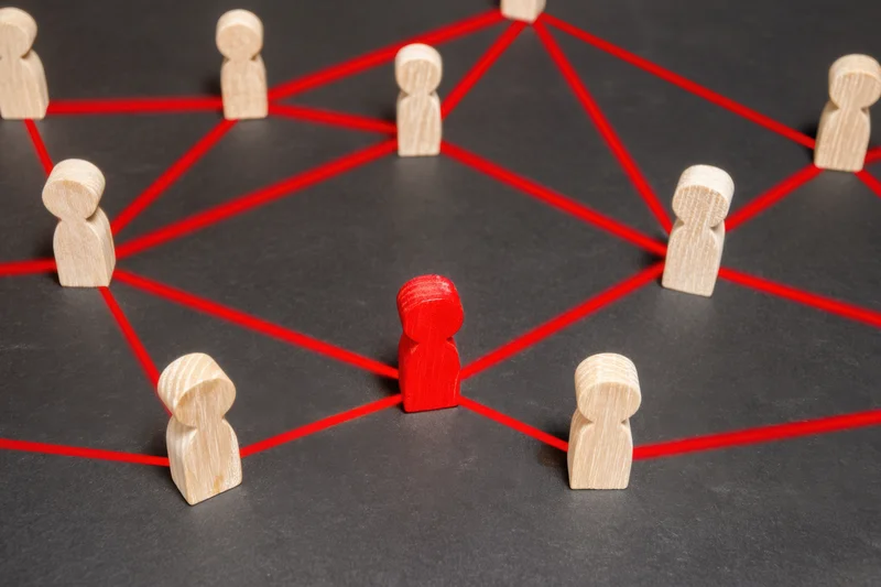 Wooden tokens connected by red strings arranged in a network pattern on a dark surface
