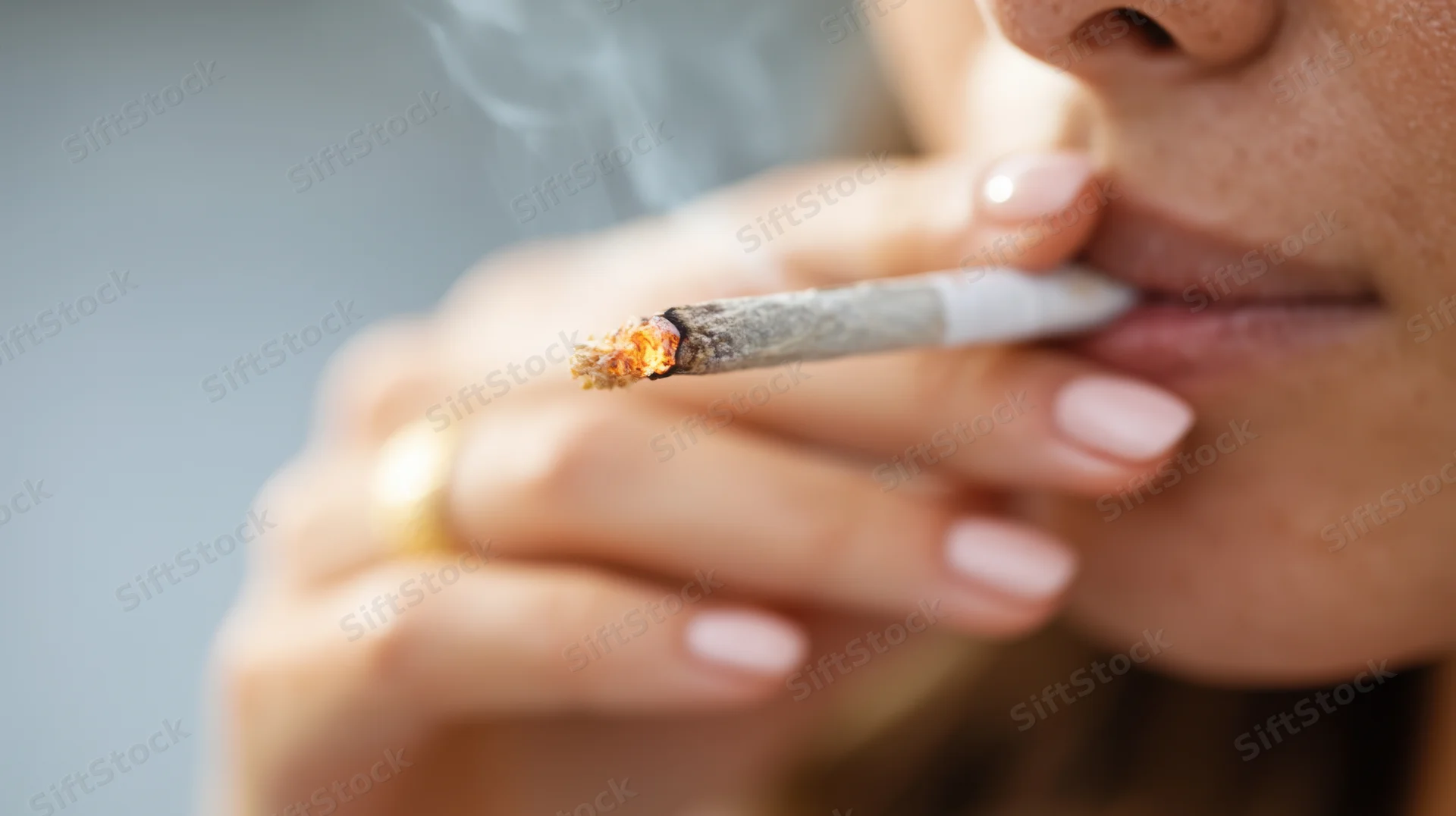 Close-up of a woman smoking a cigarette with glowing ember and smoke rising from her lips