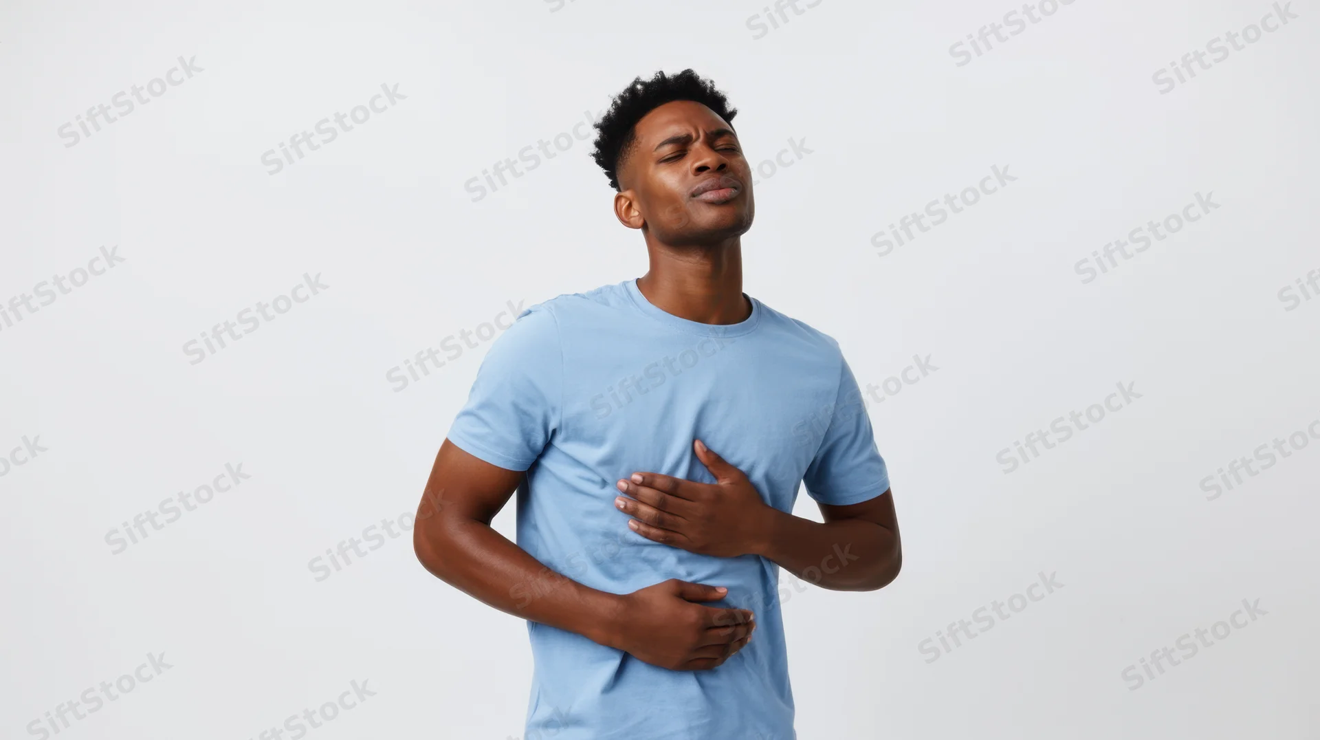 Young black man holding chest with hand, eyes closed, showing discomfort in studio setting