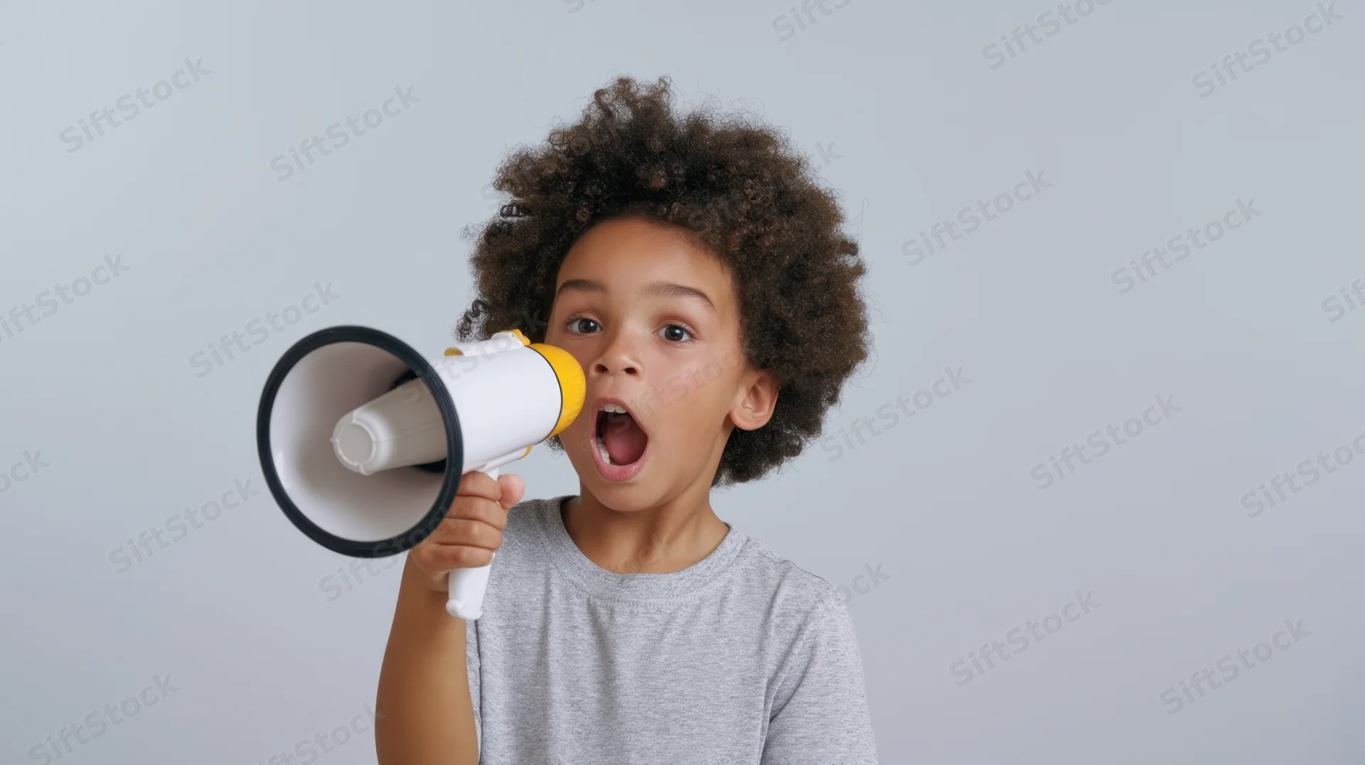 Young child shouting into a megaphone against a neutral background