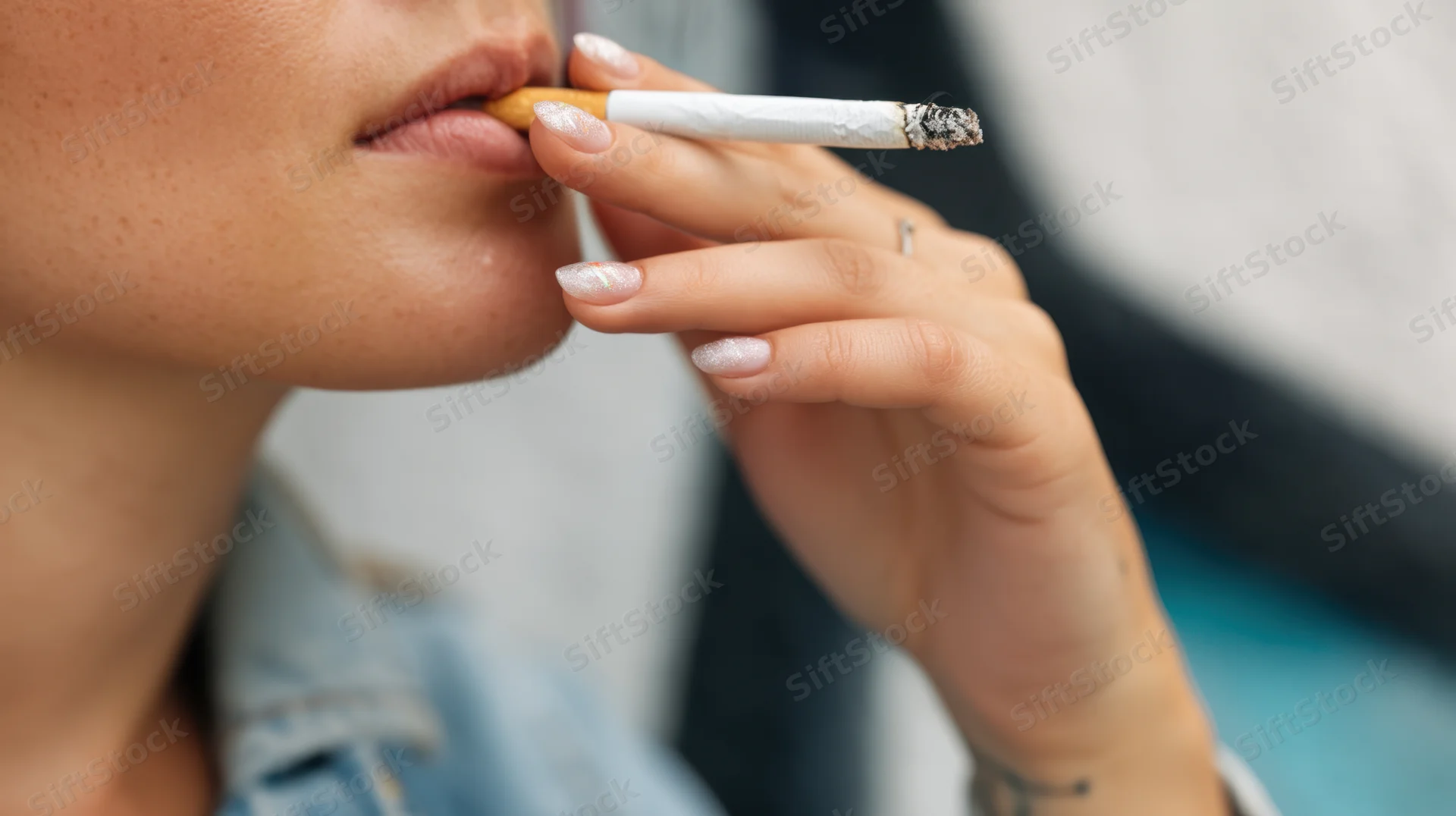 Woman smoking a cigarette with hand holding it near her lips in closeup view