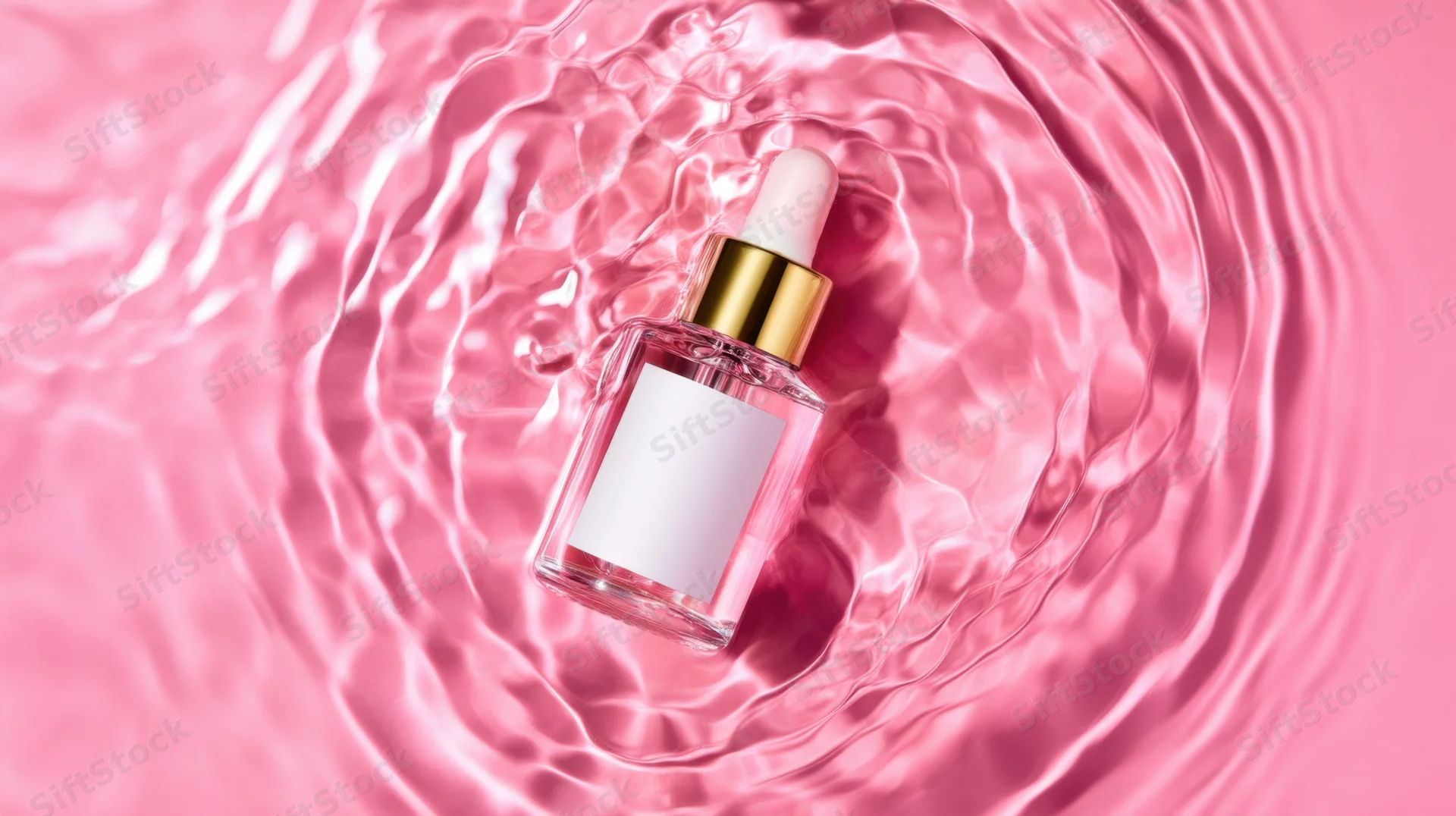 Clear glass dropper bottle with gold cap floating in rippling pink water