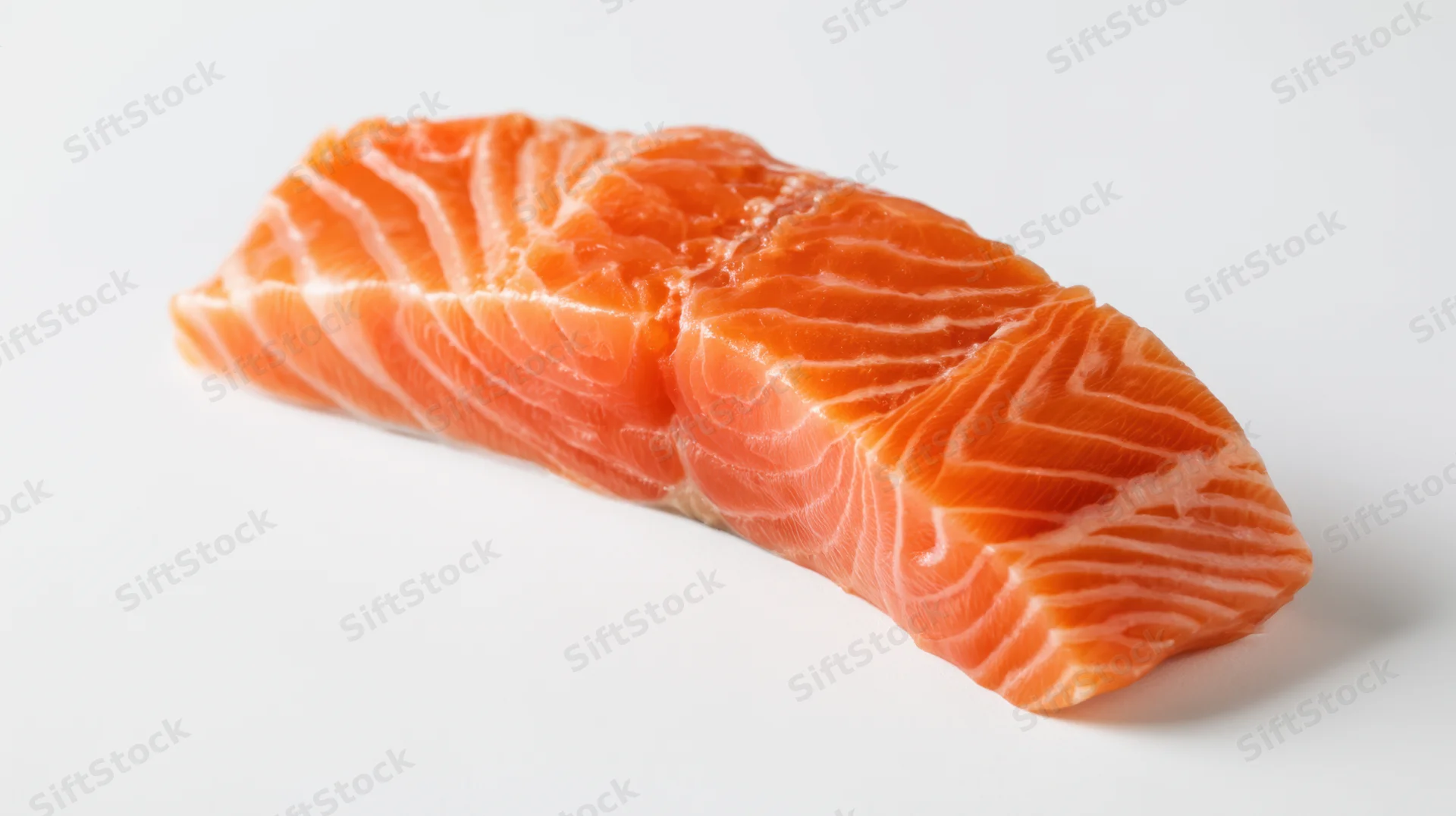 Close-up of a raw salmon fillet with visible marbling on a white surface