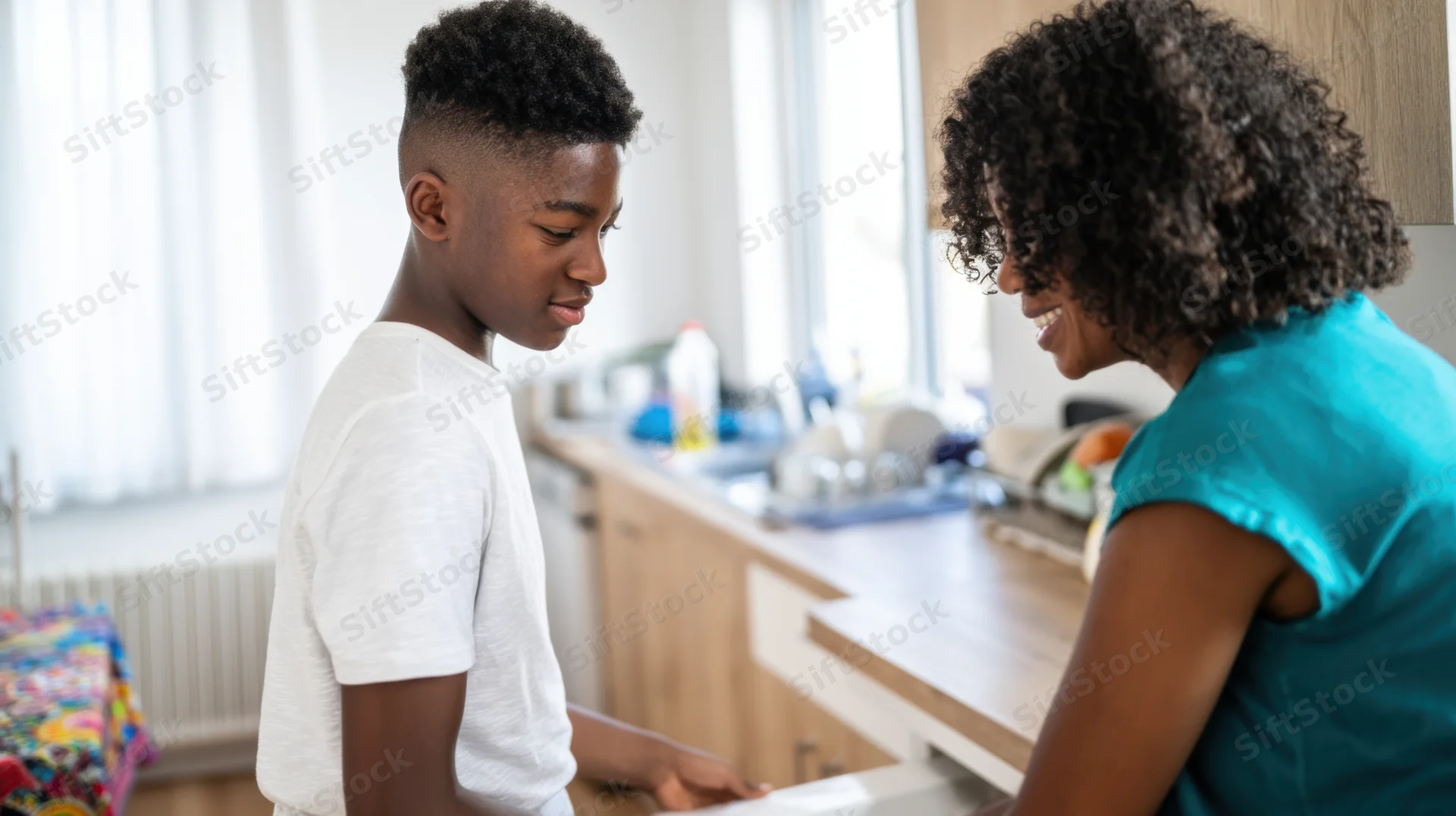 Teenage boy and woman interacting in kitchen while preparing food
