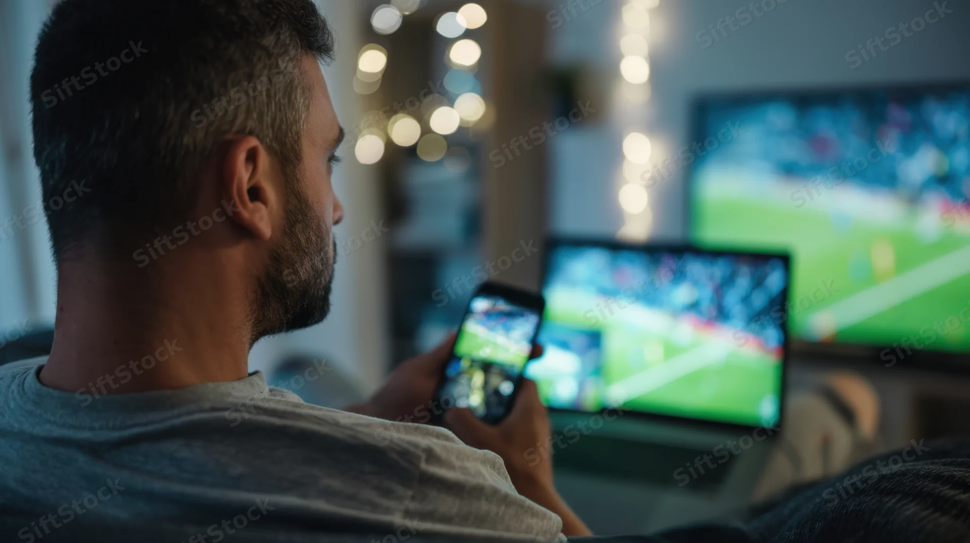 Man watching football match on multiple screens at home