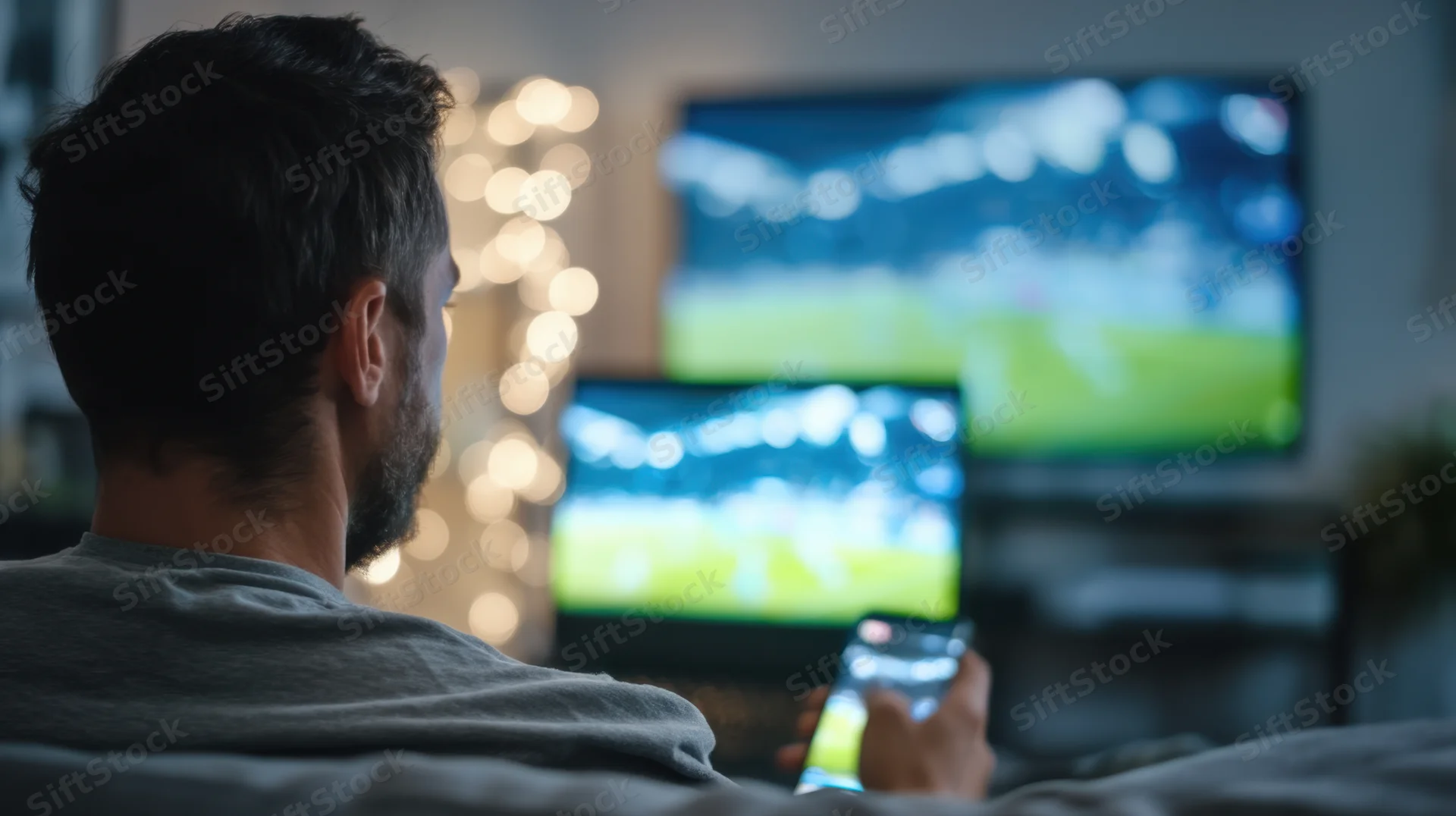 Man watching football match on multiple screens at home
