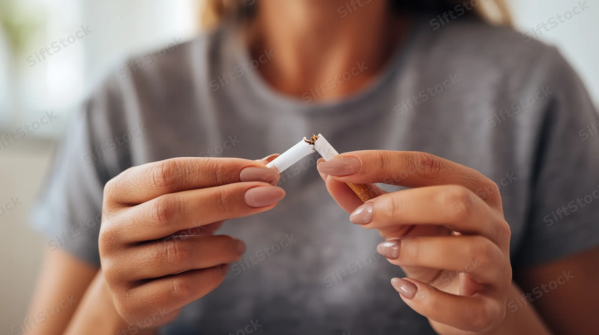Woman breaking a cigarette in her hands indoors