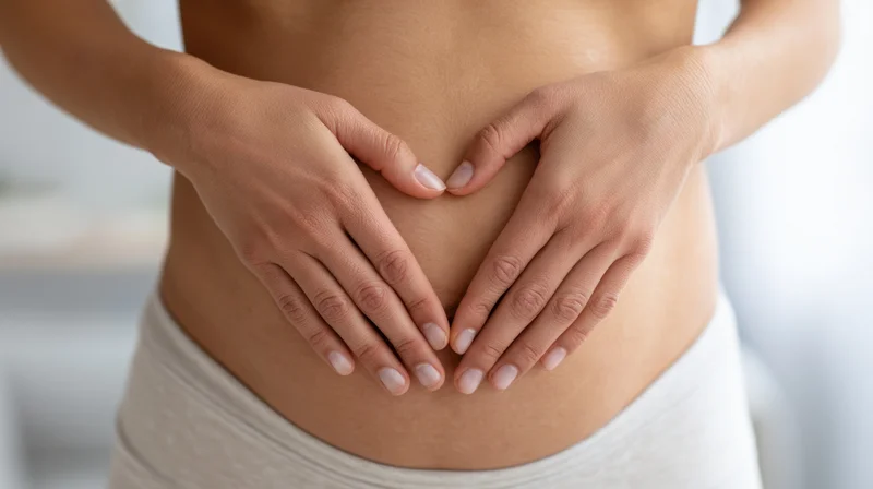 Woman’s midsection with hands forming heart shape over belly