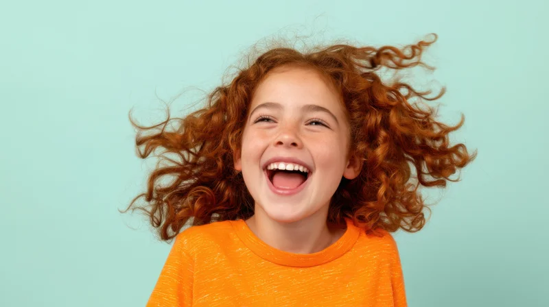 Young girl with curly red hair laughing joyfully in studio portrait