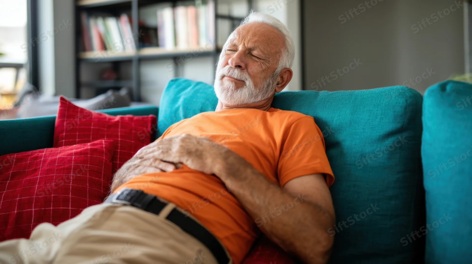 Senior man resting with eyes closed on teal couch in living room