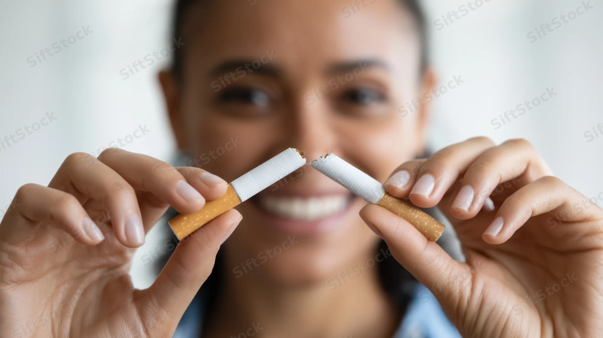 Woman smiling while holding broken cigarette in hands