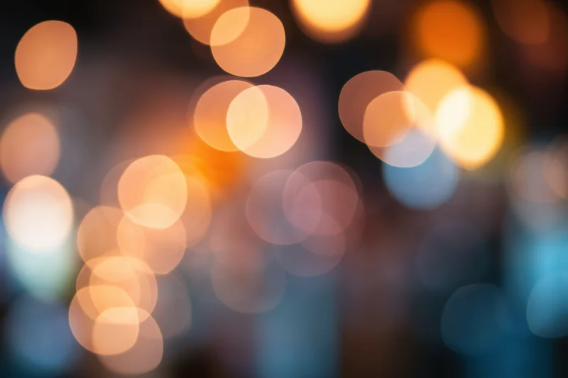 Blurred warm glowing orbs of light arranged in a soft bokeh pattern against a dark background