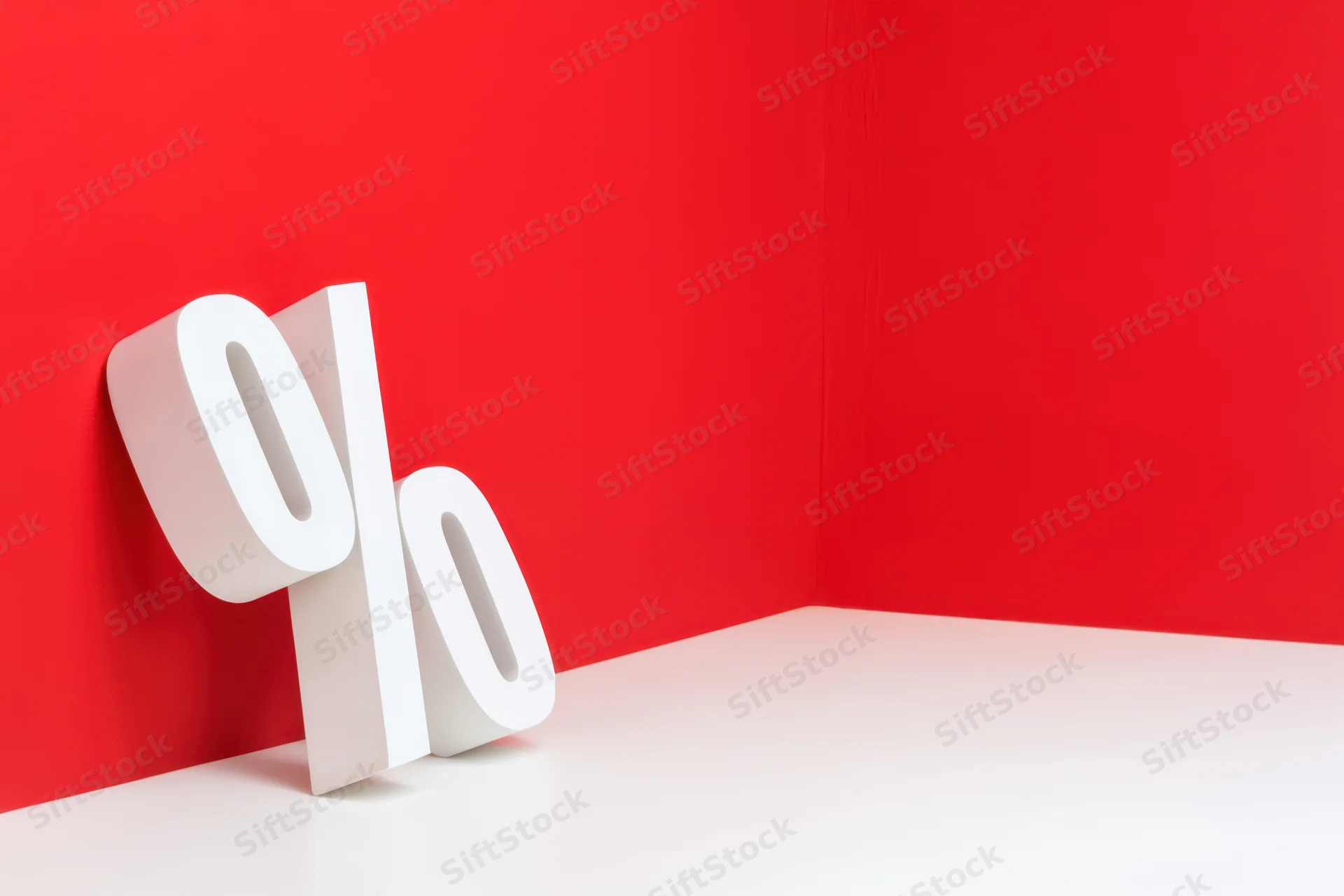 Bold white percentage symbol leaning against red wall in corner
