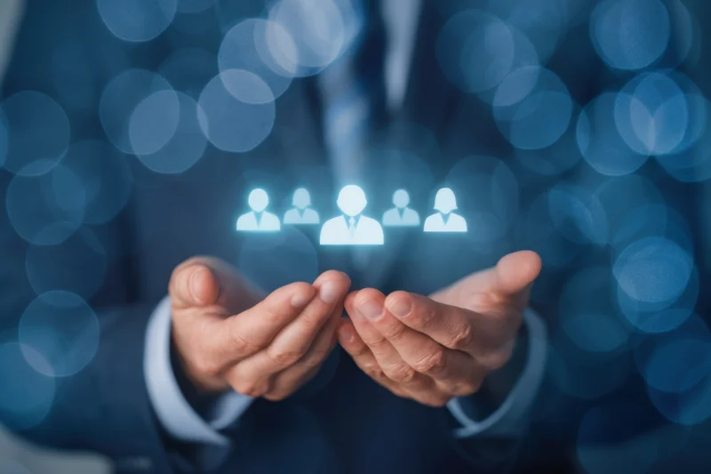 Business professional in suit holding glowing hologram of people icons with bokeh background