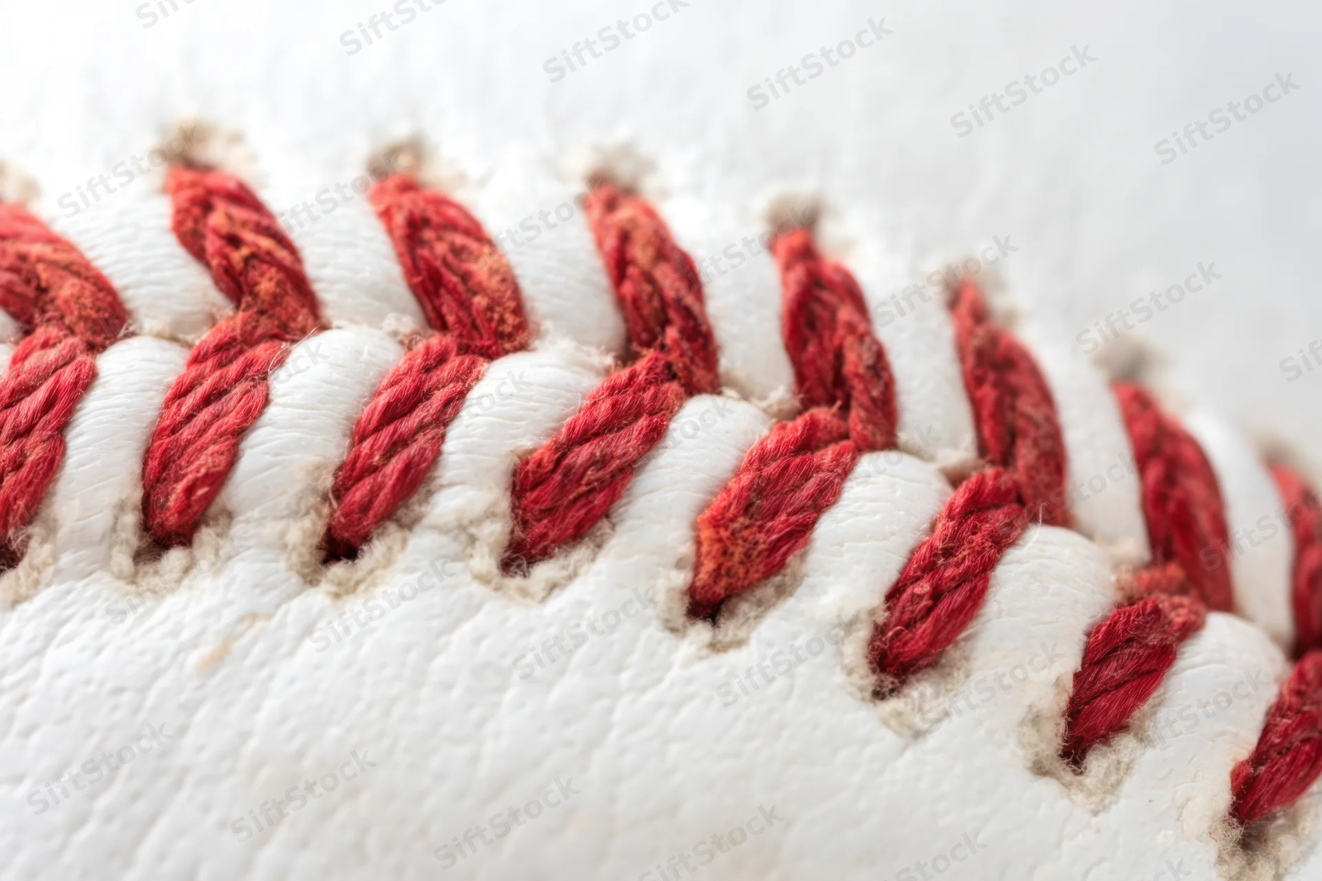 Closeup of a baseball showing detailed red stitching on white leather surface
