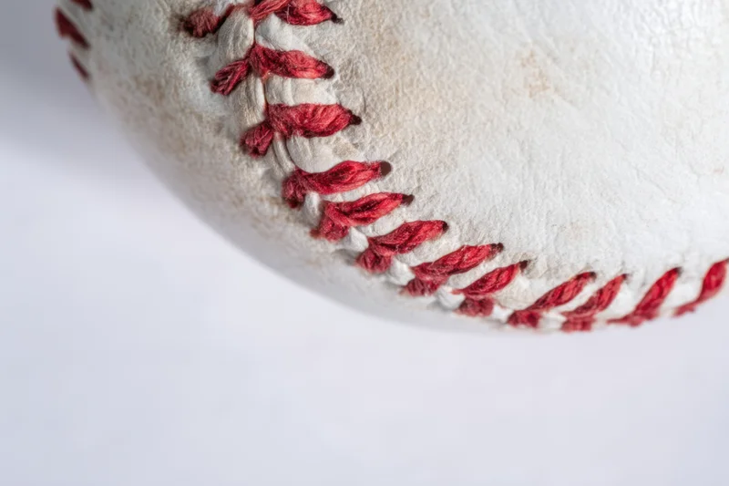 Closeup of a baseball showing detailed red stitching on white leather surface