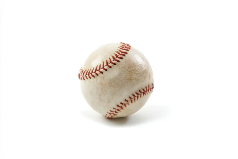 A used baseball with detailed red stitching resting on a white surface