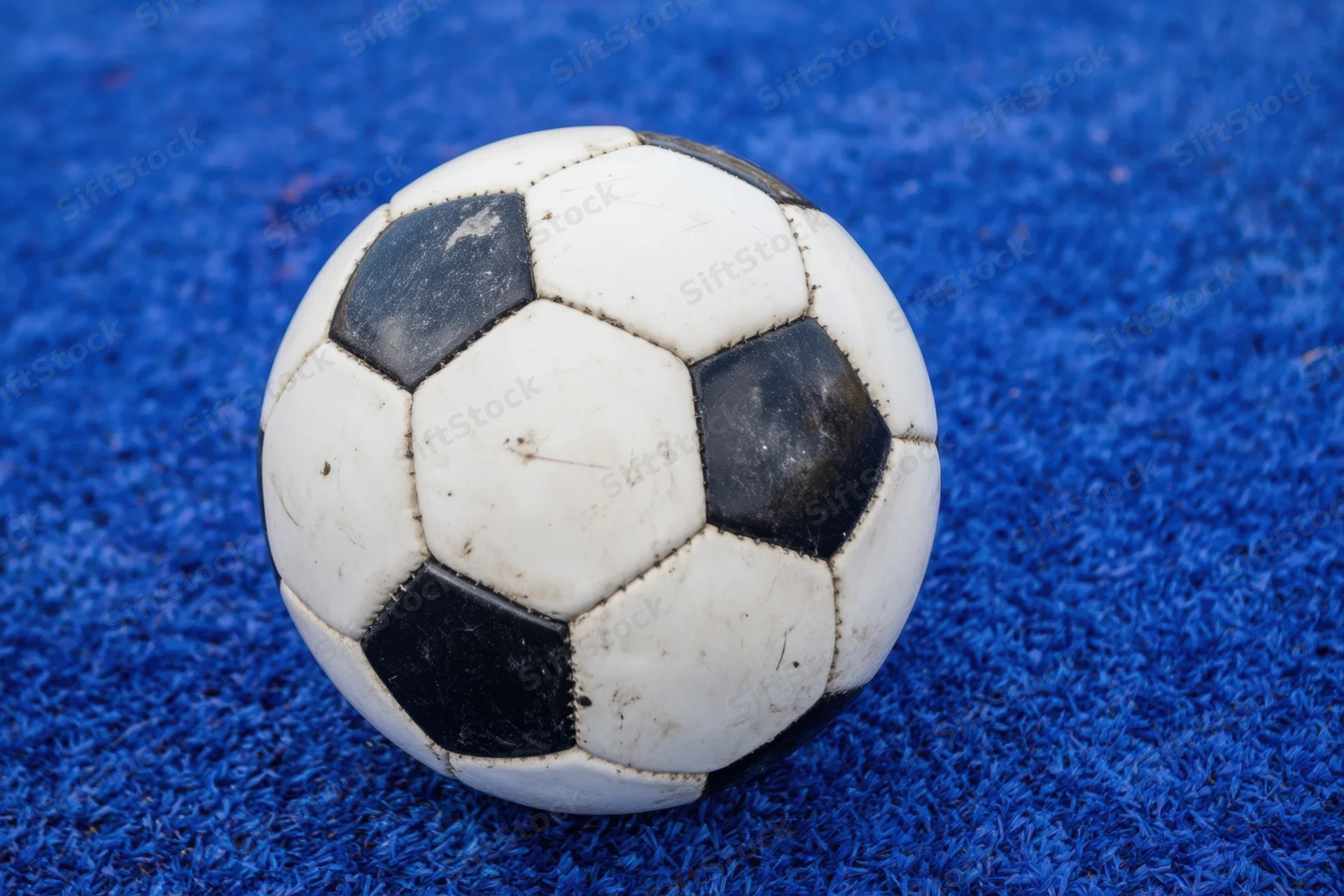 Classic black and white soccer ball resting on vibrant blue carpeted surface