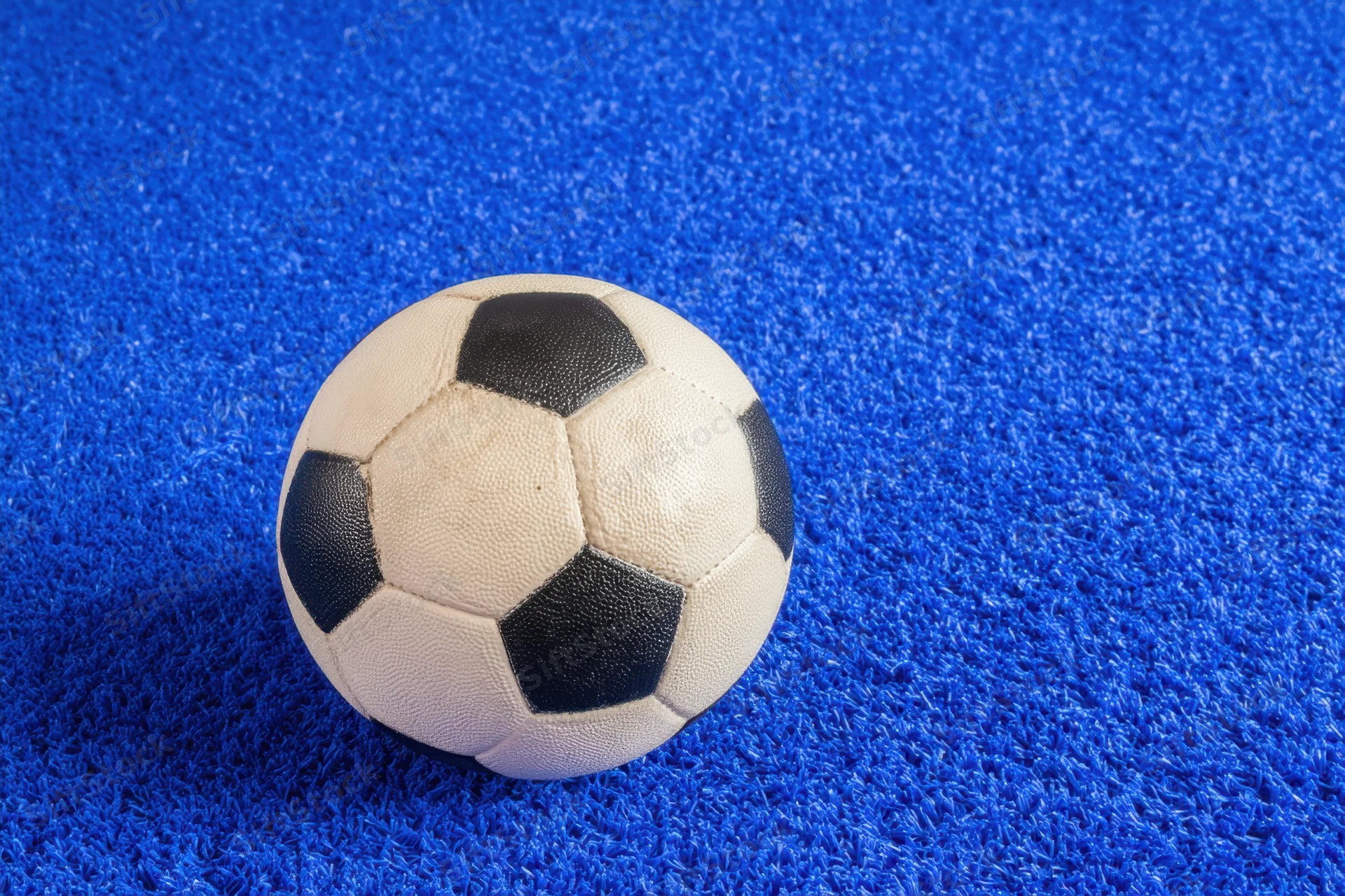 Classic black and white soccer ball resting on vibrant blue textured carpet