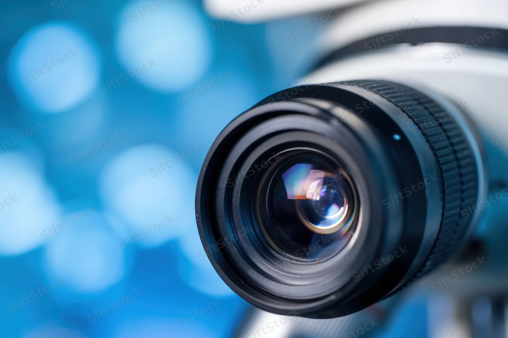 Close-up of a microscope objective lens with blue bokeh background
