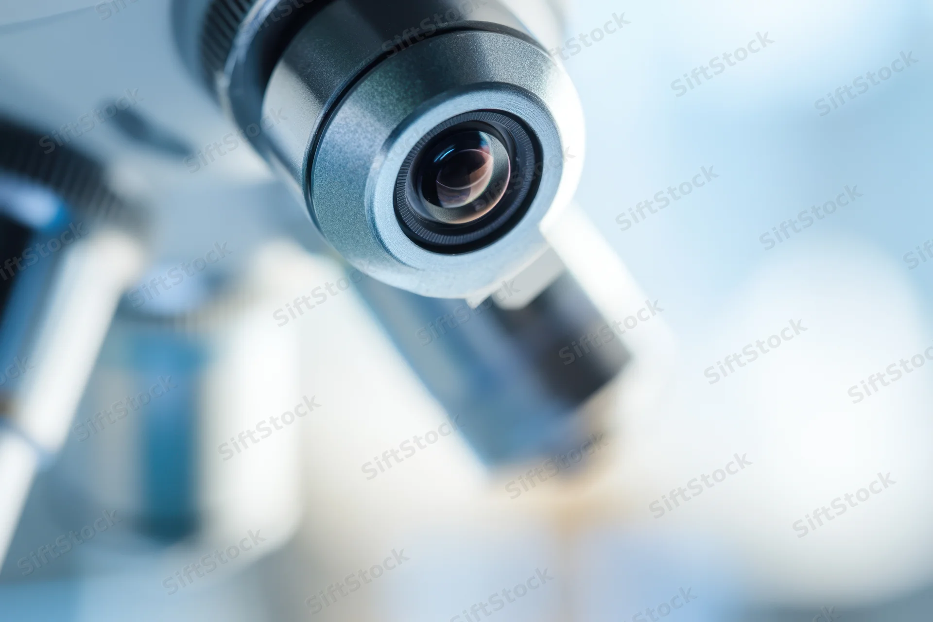 Close-up of a microscope lens with visible eyepiece and optical components in a laboratory setting