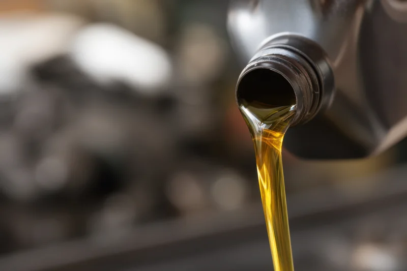 Motor oil pouring from a black bottle in a workshop setting
