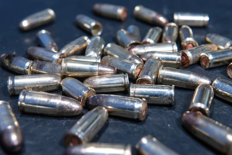 Scattered spent bullet casings on dark surface in close-up view