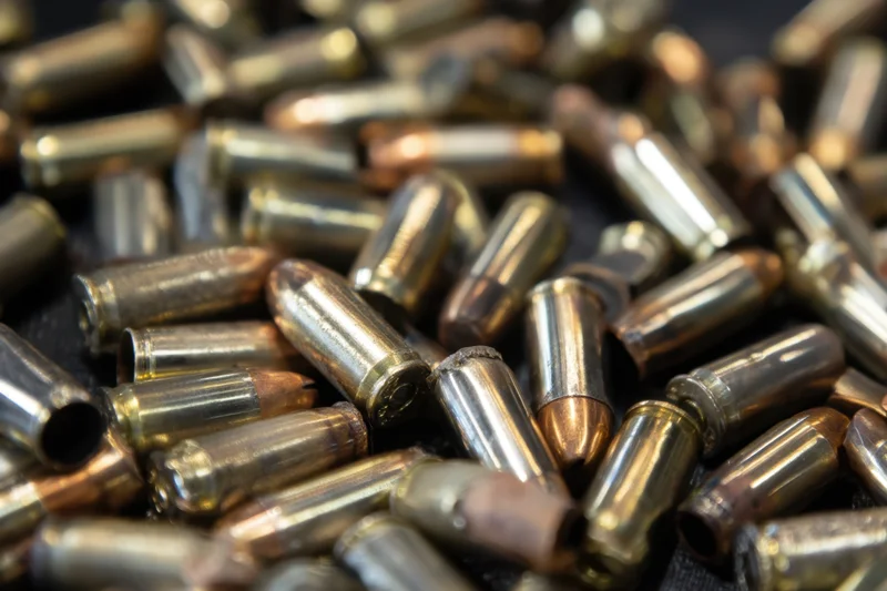 Close-up of scattered spent bullet casings on dark textured surface