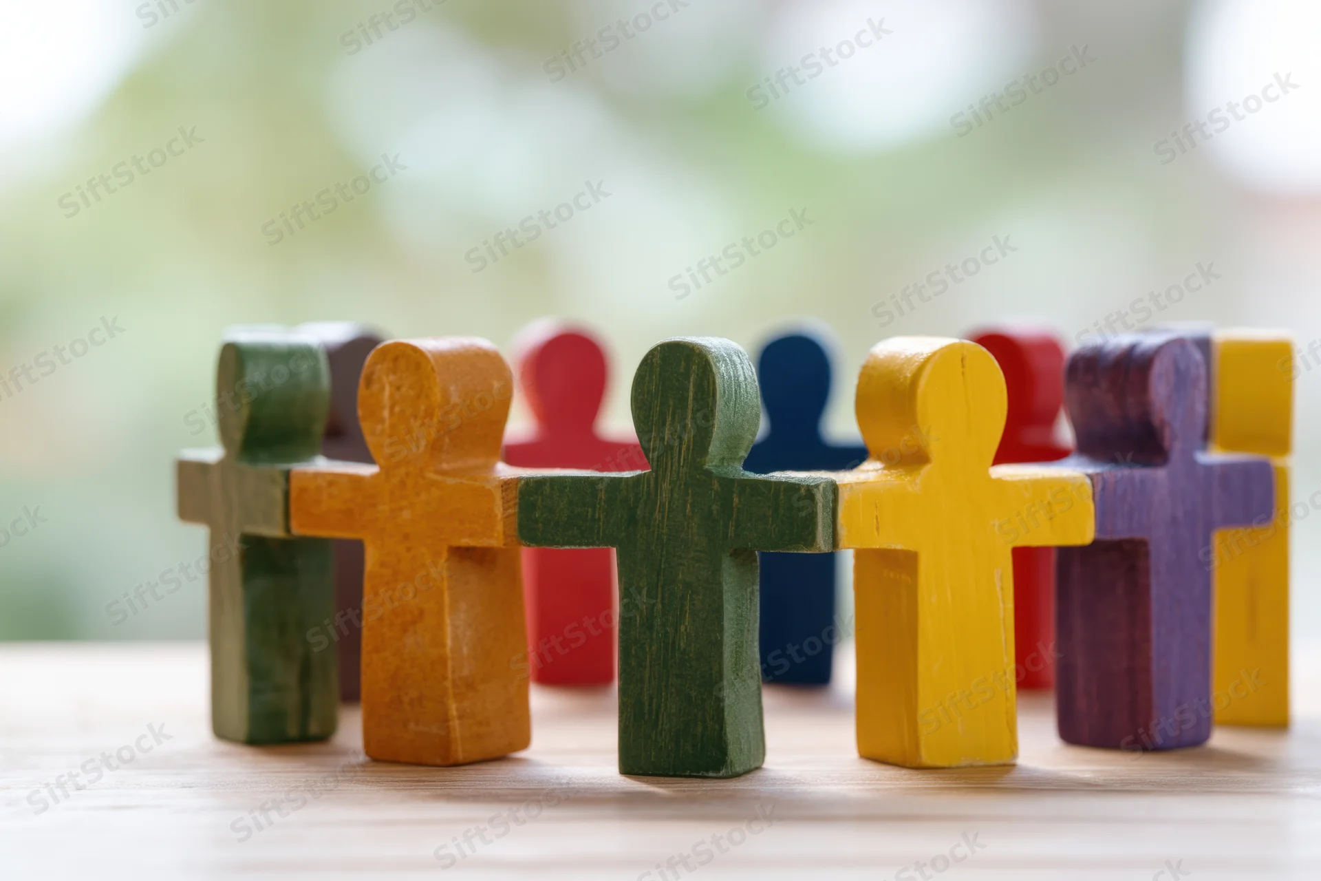 Colorful wooden figurines arranged in a connected circle on a wooden surface