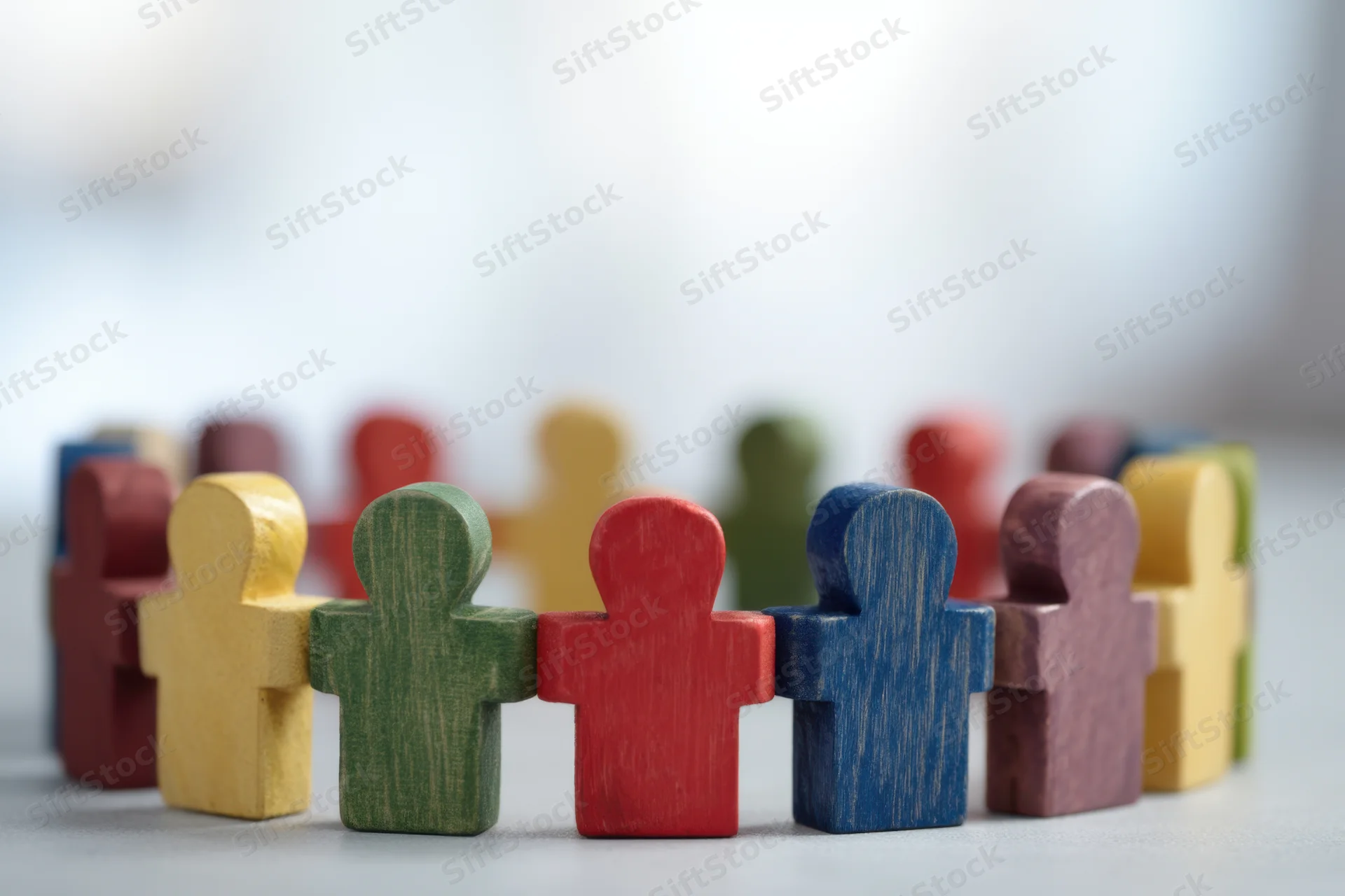 Colorful wooden figurines arranged in a connected line on a flat surface
