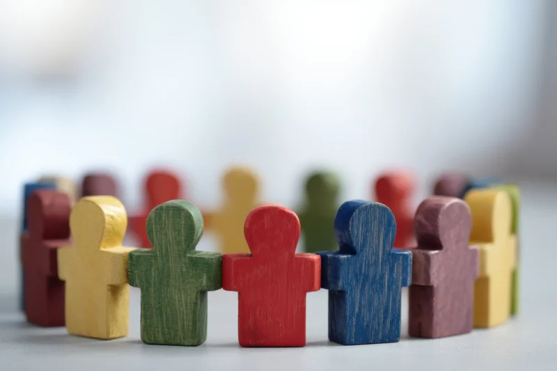 Colorful wooden figurines arranged in a connected line on a flat surface
