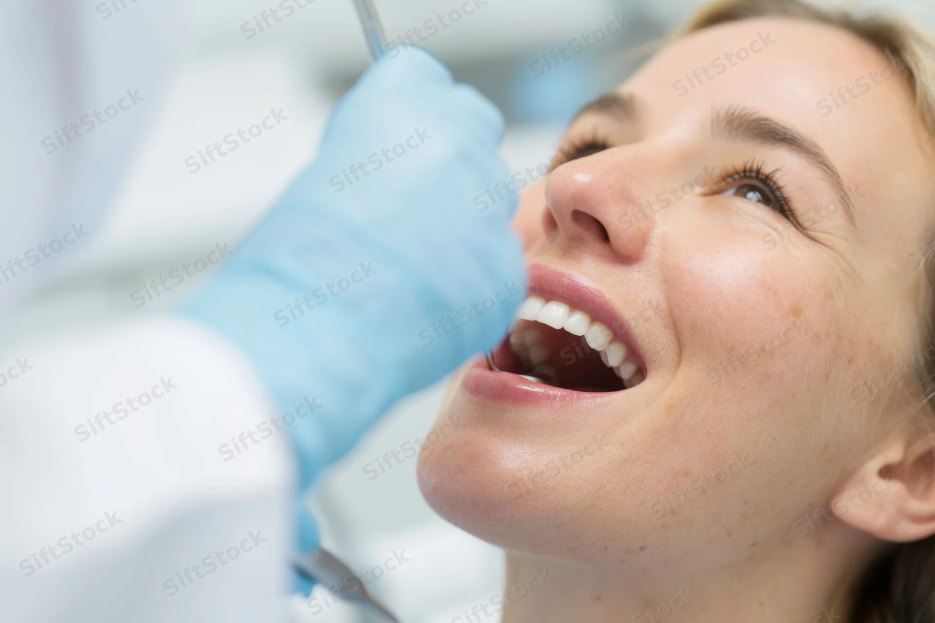Woman undergoing dental examination with dentist using mirror and probe in clinic