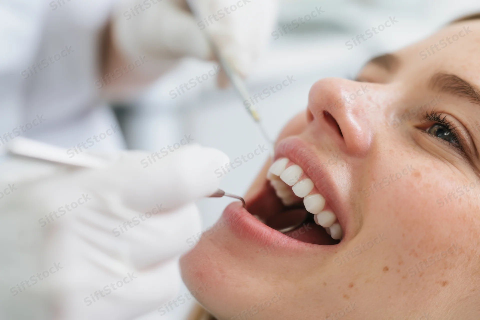 Close-up of a young woman undergoing dental examination with dentist using tools in a clinic