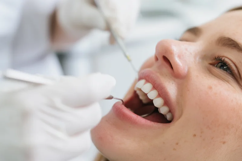 Close-up of a young woman undergoing dental examination with dentist using tools in a clinic