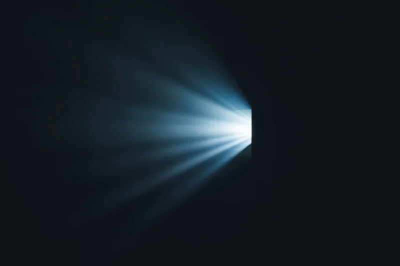 Radiant beam of light emerging from a narrow opening in darkness