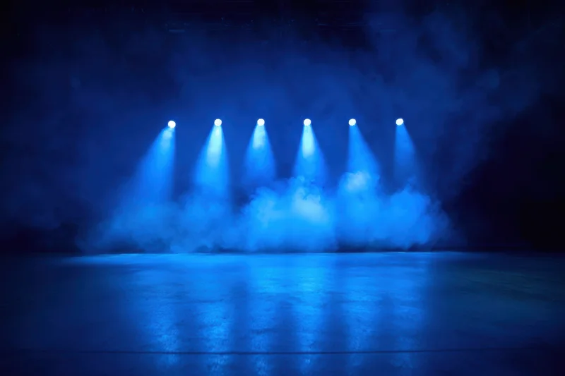 Stage illuminated by blue spotlights with smoke and reflective floor