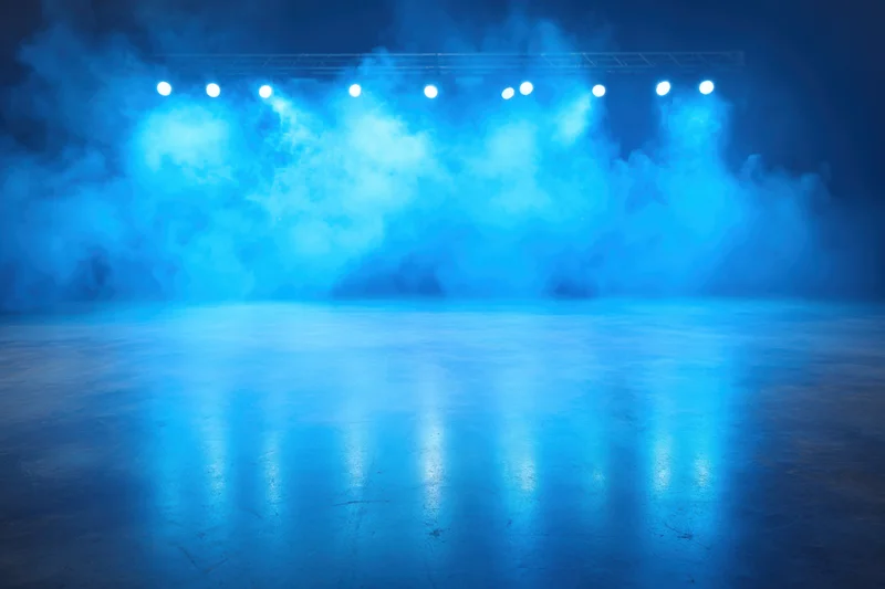 Stage illuminated by blue spotlights with smoke and reflections on the floor