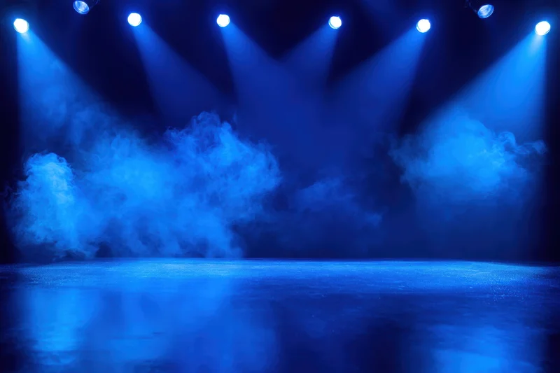 Stage illuminated by blue spotlights with smoke and reflective floor